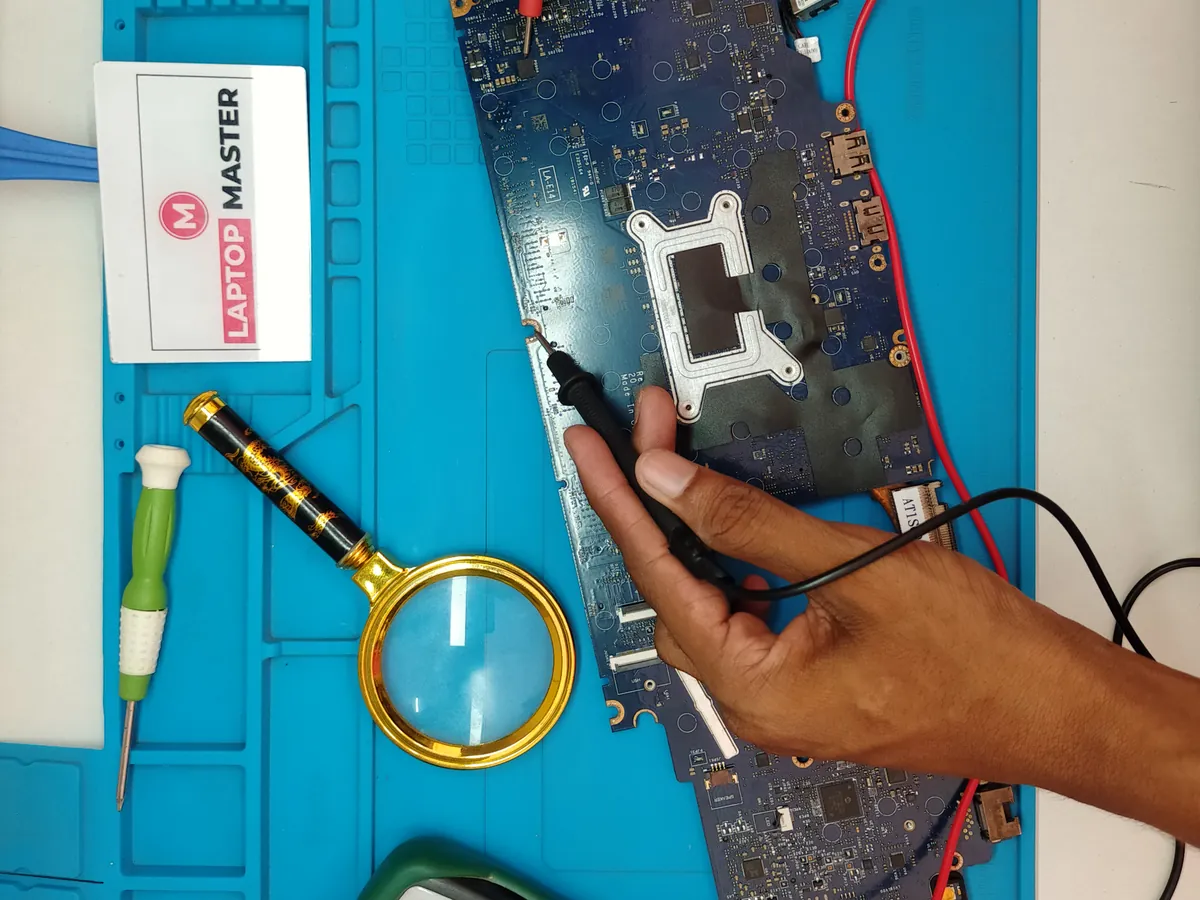 Motherboard fault testing with a multimeter and magnifier at LAPTOP MASTER